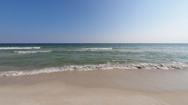 A beach with clear skies and calm waves. - Beachview condo with community pools, grills, and internet (Gulf Shores)