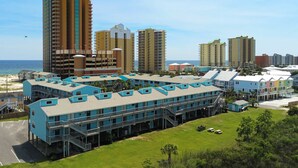 A multi-story hotel with a central courtyard, a pool, and a view of the beach. - Beachview condo with community pools, grills, and internet (Gulf Shores)