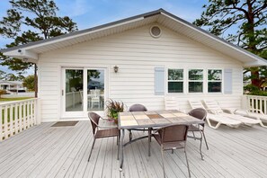 A house with a deck, a dining table with chairs, and a patio area. - Dog-friendly bay-view home with central AC - snowbirds welcome (Orange Beach)