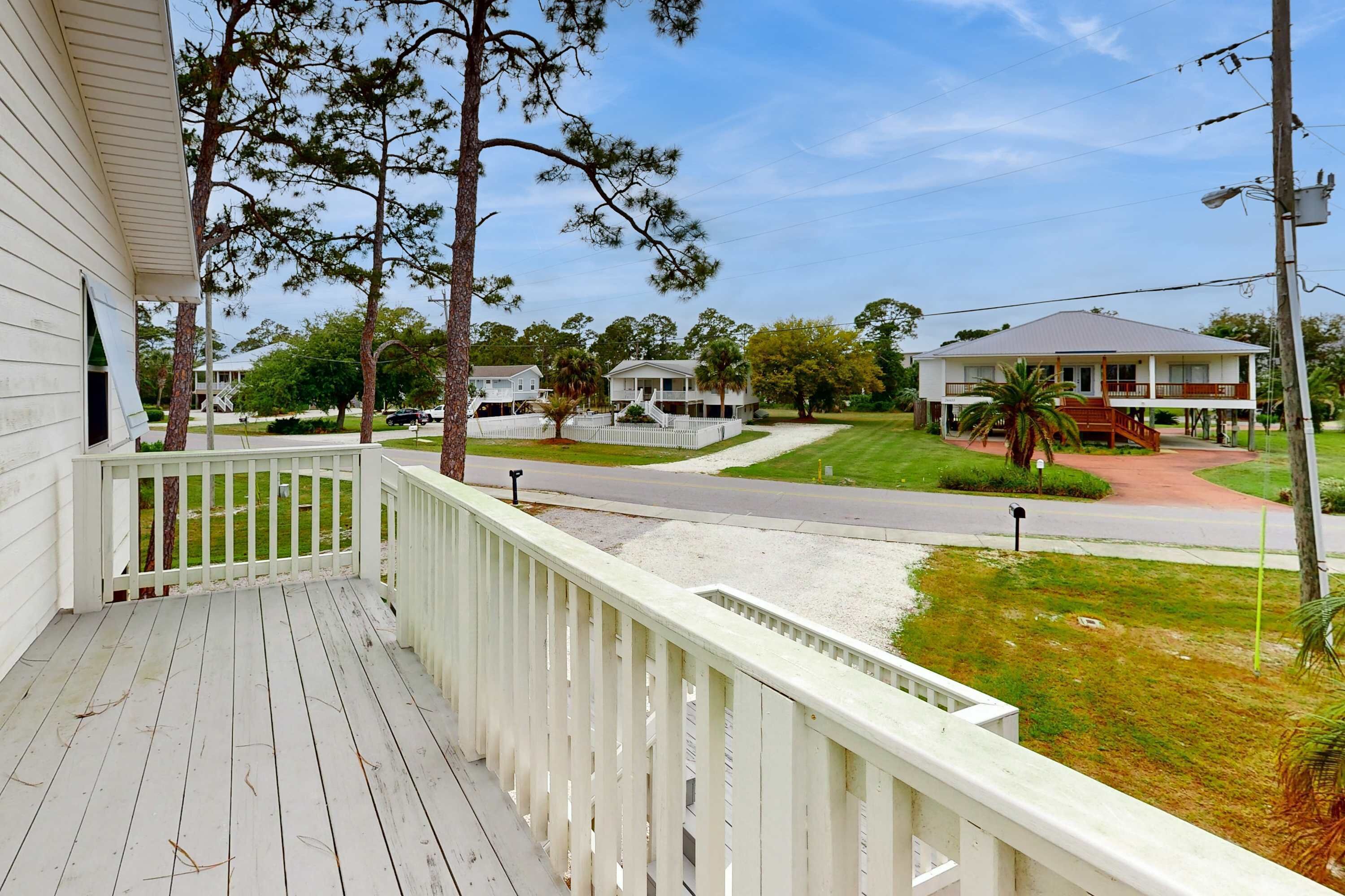 A residential area with a white house, a porch, and a street.