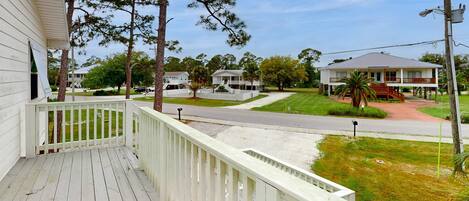 A residential area with a white house, a porch, and a street.