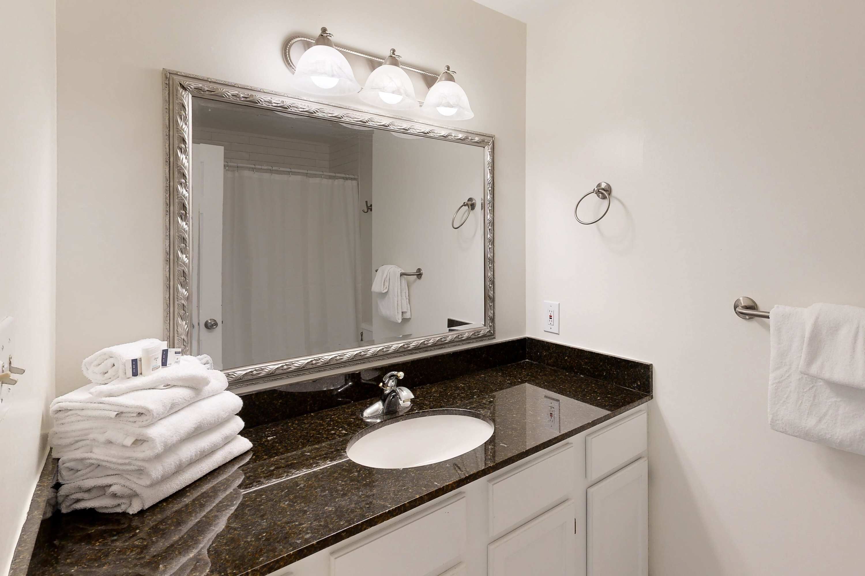 Un bagno con uno specchio grande, un lavandino e un porta asciugamani.