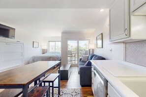 Ein kompakter Wohnbereich mit Küchenzeile, Essbereich, Sofa und Balkon mit Blick.