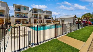 A residential building with a swimming pool, fenced yard, and multiple balconies. - Brillant cottage near beach with shared pool, balcony, and washer & dryer (Gulf Shores)