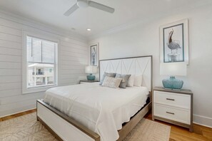 A bedroom with a bed, nightstands, a ceiling fan, and artwork on the walls. - Brillant cottage near beach with shared pool, balcony, and washer & dryer (Gulf Shores)