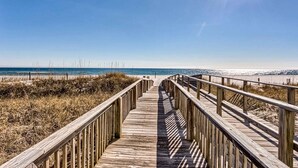 Una passerella di legno che conduce a una spiaggia sotto un cielo sereno.