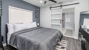 Ein modernes Schlafzimmer mit Bett, Deckenventilator, Schiebetürenschrank und Spiegel.