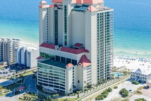 A high-rise hotel with multiple floors, a rooftop pool, and a beach view. - Gulf-front retreat with great view, balcony, pools, lazy river, & hot tubs (Orange Beach)
