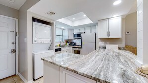 Une cuisine moderne avec des armoires blanches, un comptoir en granit et des appareils électroménagers intégrés.
