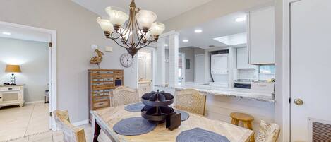 Un comedor con candelabro, una mesa de madera y sillas.