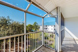 Ein überdachter Balkon mit Blick auf ein Wohngebiet, darunter ein weißes Gebäude mit Balkon.