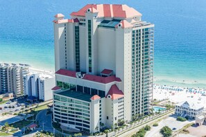 A high-rise hotel with multiple floors, a pool, and a beach view. - Gulf-front corner condo with stunning view, balcony, pools, hot tubs, & gym (Orange Beach)