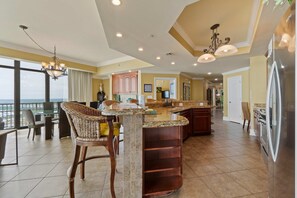 A spacious kitchen with a large island, modern appliances, and a view to the outside. - Gulf-front corner condo with stunning view, balcony, pools, hot tubs, & gym (Orange Beach)