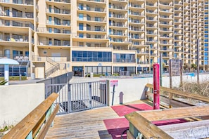 A multi-story hotel with balconies, a pool area, and a wooden deck. - Beachfront condo with Gulf views, balcony, pools, hot tubs & sports courts (Orange Beach)