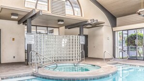 En swimmingpool med en kaklad vägg, ett bubbelbad och ett täckt område med utsikt över omgivningen.