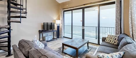 A living room with a sofa, coffee table, TV, and a balcony with a view.