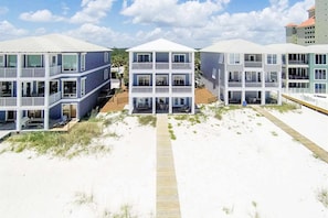 Ein Strandgrundstück mit mehrstöckigen Gebäuden, einer Holzpromenade und einem Sandstrand.