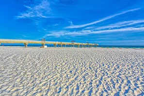 A beach with a pier extending into the water, sandy beach, and clear blue sky. - Beachfront Condo w/Jaw-Dropping Views, Shared Pool, Gym, Private Balcony (Orange Beach)