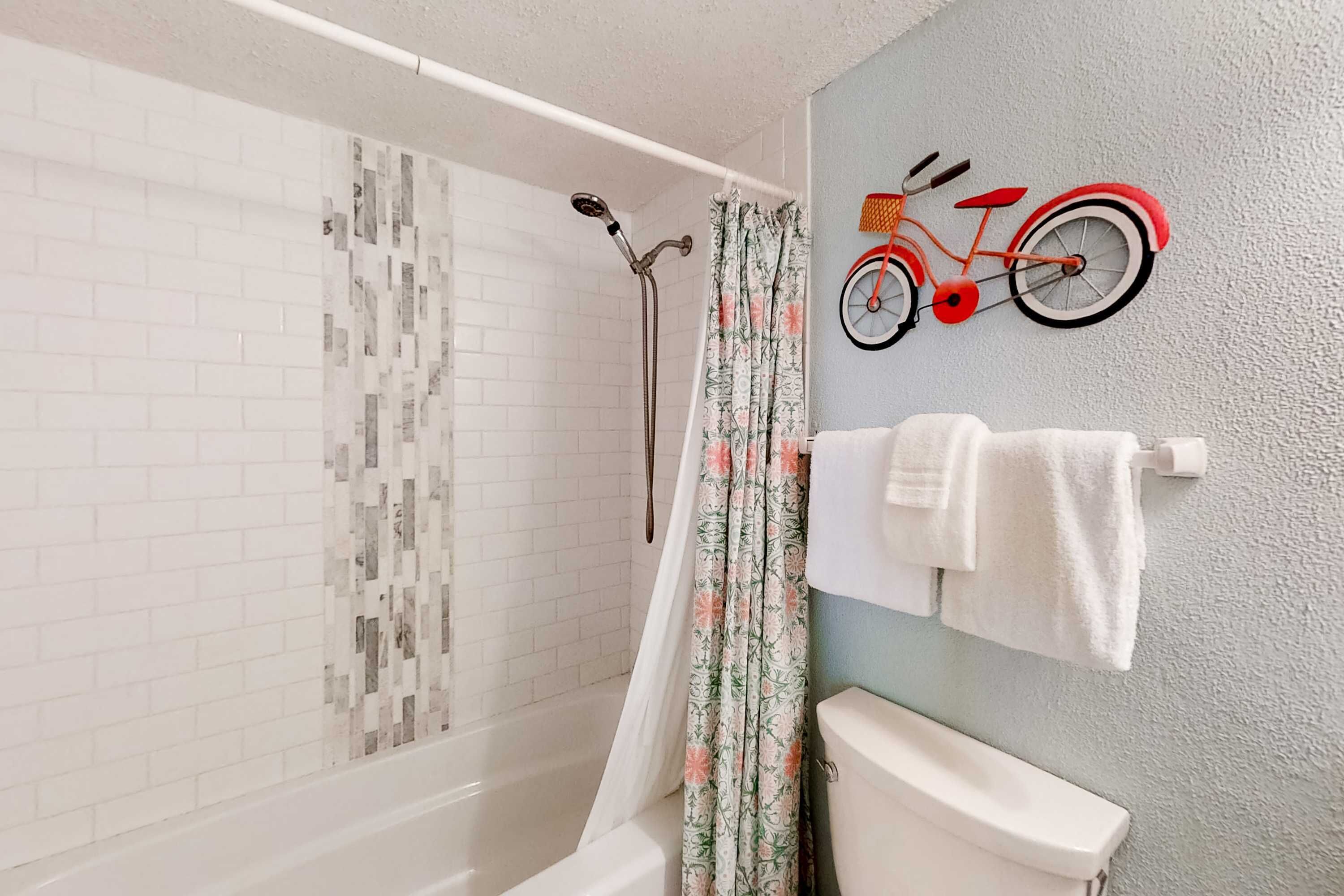 A bathroom with a shower, toilet, and a wall-mounted bicycle decoration.