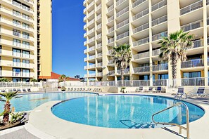 Ein Hotel mit großem Pool, mehreren Balkonen und Palmen.