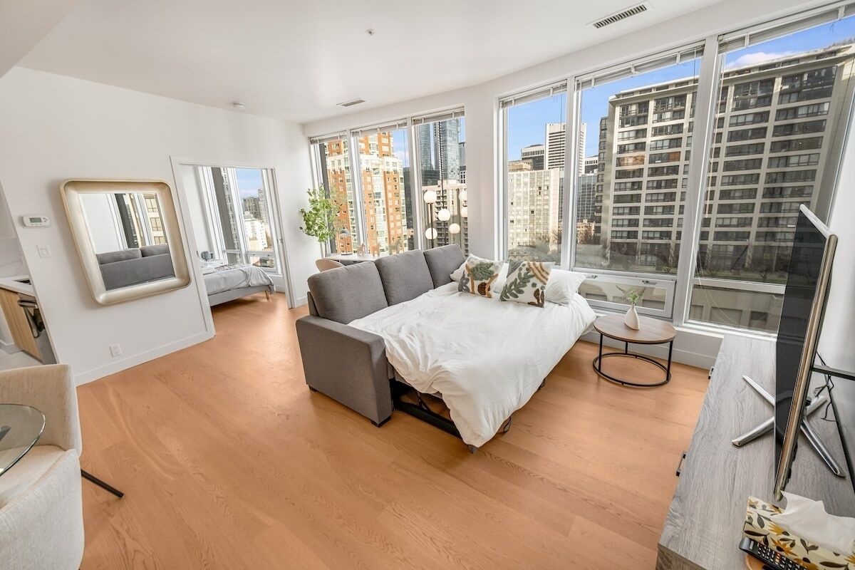 A modern bedroom with a large bed, a sofa, a small table, and a TV.