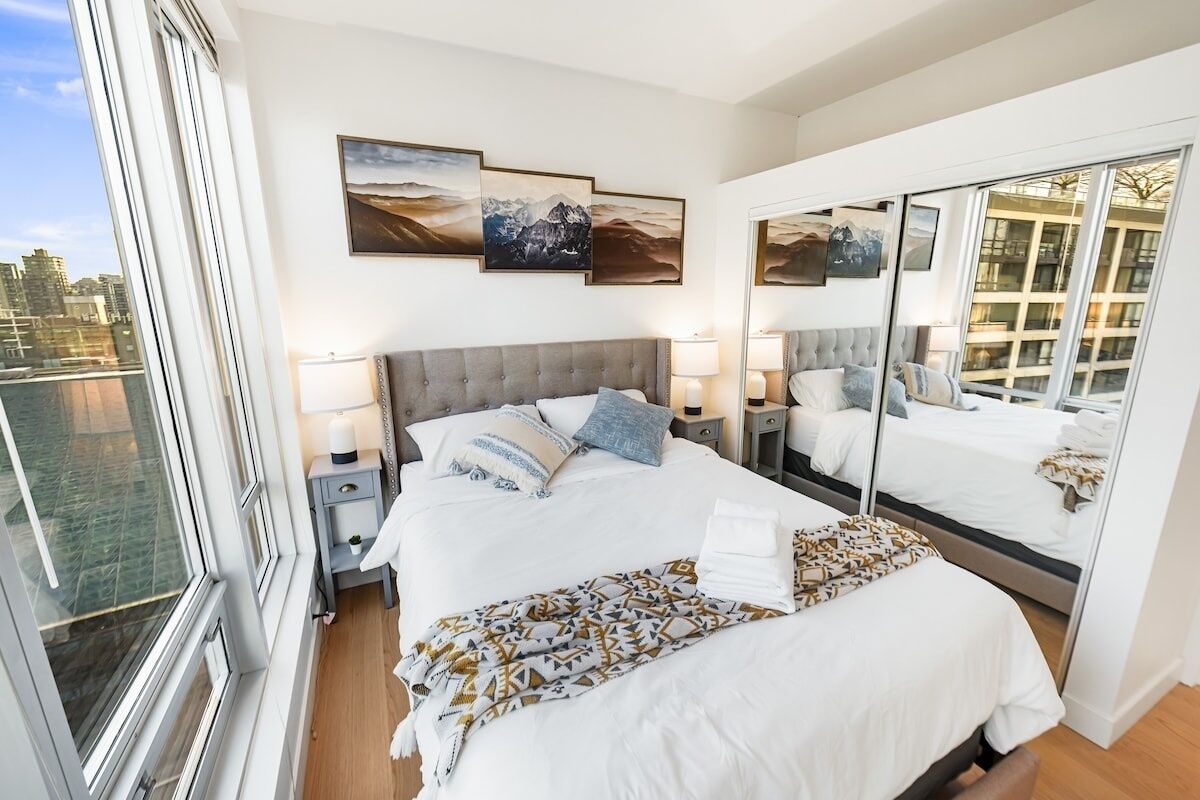 Um quarto moderno com uma cama grande, um espelho e obras de arte na parede.