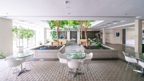 A modern indoor space with a central garden area, surrounded by seating arrangements and a glass table. - Modern & Cozy Stay in Prime DT (Vancouver)