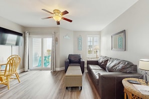 A living room with a ceiling fan, a sofa, a chair, a small table, and a wicker ottoman. - Gulf Coast condo with a pool, gym, boat launch, & nearby beach access (Orange Beach)