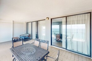Ein Balkon mit Tisch und Stühlen, einer Couch und Blick auf das Meer.