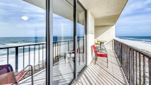 Ein Balkon mit Blick auf den Strand, einem Tisch und Stühlen.