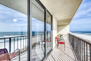 A balcony with a view of the beach, a table, and chairs. - Fourth-floor beach condo w amazing views, indoor pool, & beach access (Orange Beach)