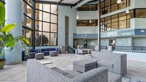 Eine geräumige Lobby mit Sitzgelegenheiten, großen Fenstern und einem Fliesenboden.