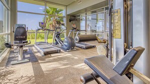 A gym with exercise equipment, large windows, and a ceiling fan. - Beachfront property with Gulf-view balcony, outdoor pool & hot tub - near shops (Orange Beach)