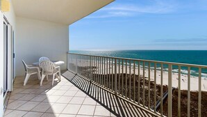 A balcony with a view of the beach, a table with chairs, and a railing. - Beachfront property with Gulf-view balcony, outdoor pool & hot tub - near shops (Orange Beach)