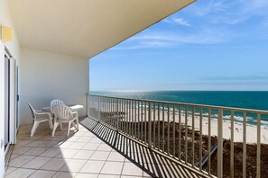 A balcony with a view of the beach, a table with chairs, and a railing. - Beachfront property with Gulf-view balcony, outdoor pool & hot tub - near shops (Orange Beach)
