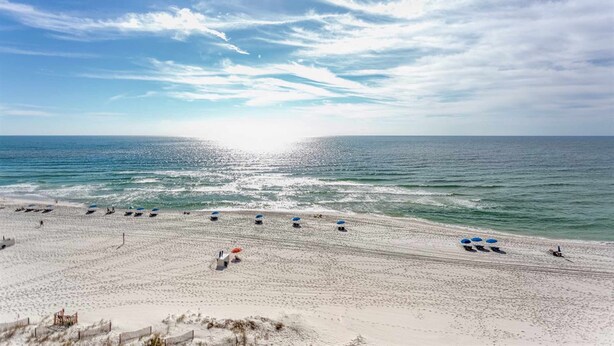 A beach with umbrellas and sun loungers, a fence, and the ocean. - Gulf-front condo w/ beach access, indoor/outdoor pool, & tennis courts (Orange Beach)