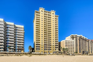 A high-rise hotel with multiple balconies, a beach view, and a sandy foreground. - Spacious condo with Gulf-front views & access to pools, hot tub, gym (Orange Beach)