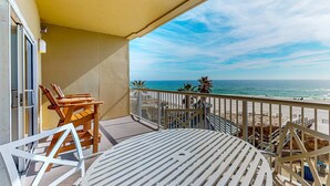 A balcony with a view of the ocean, a table, and two chairs. - Spacious condo with Gulf-front views & access to pools, hot tub, gym (Orange Beach)