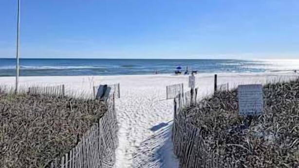 A beach pathway leading to the ocean with a fence on either side. - Gulf front condo with onsite snack bar, three shared pools, and internet (Orange Beach)