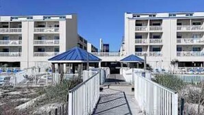 A hotel with multiple balconies, a covered walkway, and a pool area. - Gulf front condo with onsite snack bar, three shared pools, and internet (Orange Beach)