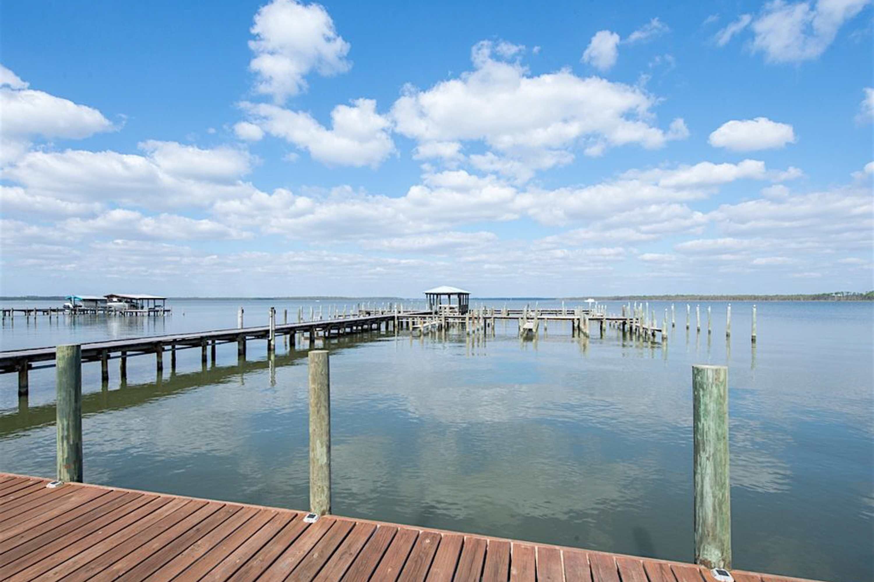 A wooden pier extending into calm water with a small structure at the end.