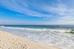 A beach with sand and waves. - Beachfront 10th-floor condo with balcony, pools, hot tub, gym, WiFi, & AC (Orange Beach)