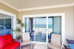 A balcony with a view of the beach, a red sofa, wicker chairs, and a potted plant. - Beachfront at Marlin Key, Dazzling Views, Pool & Private Boardwalk to Sand (Orange Beach)