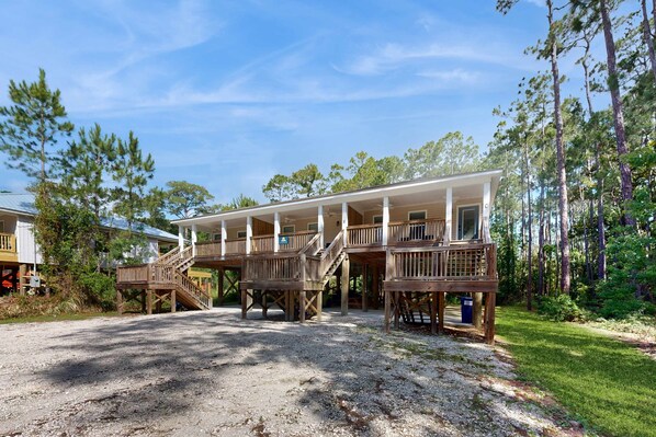 A two-story wooden structure with a covered porch and a gravel driveway.