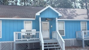 Ein blaues Gebäude mit Veranda, zwei Stühlen und einer Tür mit der Aufschrift 'Beach Inn'.