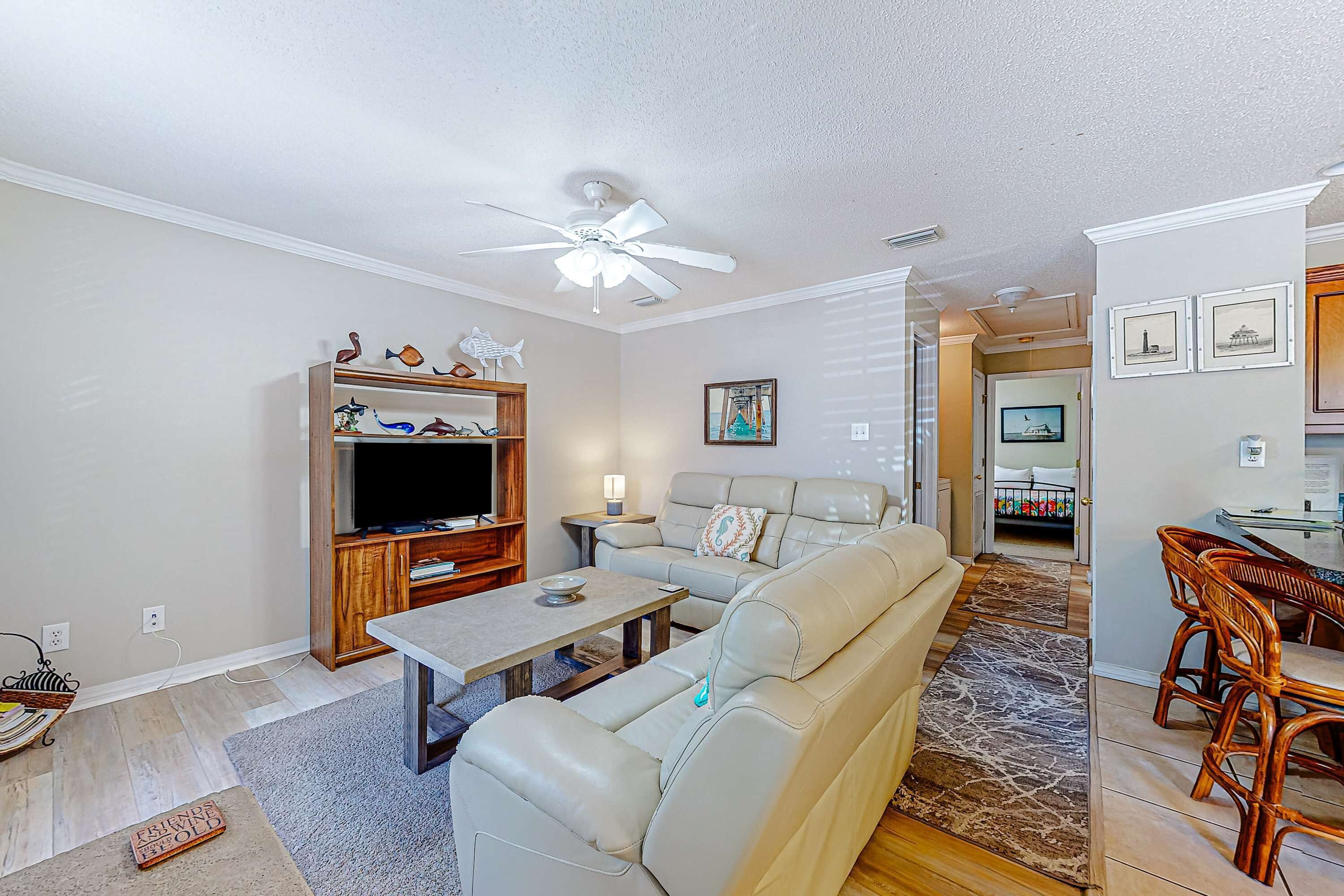 A living room with a sofa, TV, wooden entertainment unit, and a dining area with chairs.