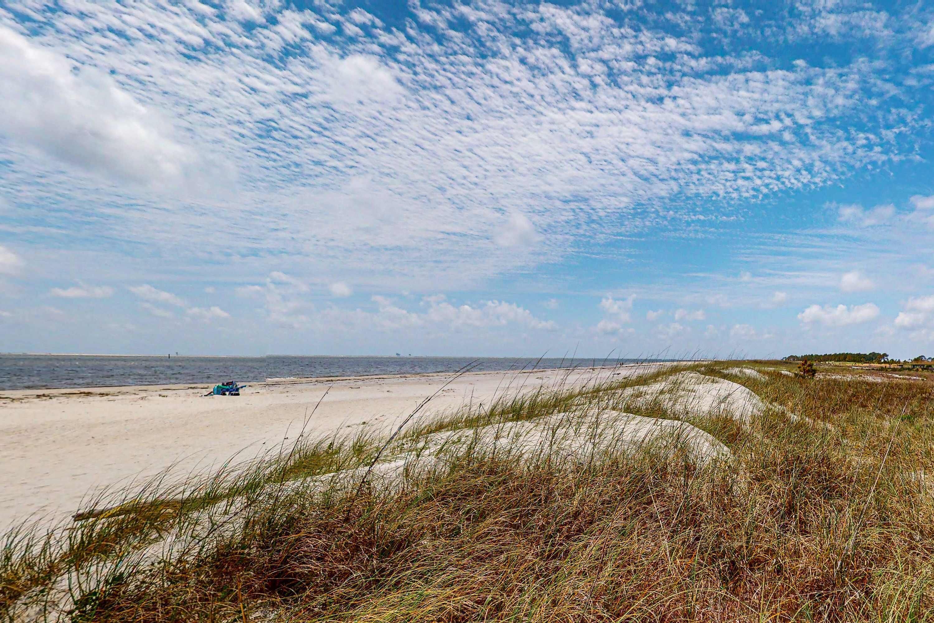 Una playa con dunas de arena y cielo despejado.
