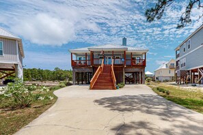 A two-story house with a balcony, a staircase, and a flag. - Dog friendly coastal home with beach access, pool, pickleball & golf nearby (Dauphin Island)