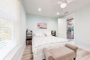 A bedroom with a bed, a bench, a painting, and a closet.