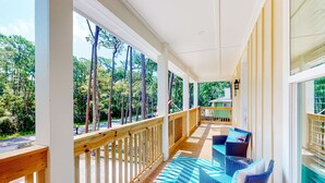 Eine überdachte Veranda mit Holzgeländer, Gartenmöbeln und Blick auf Bäume.
